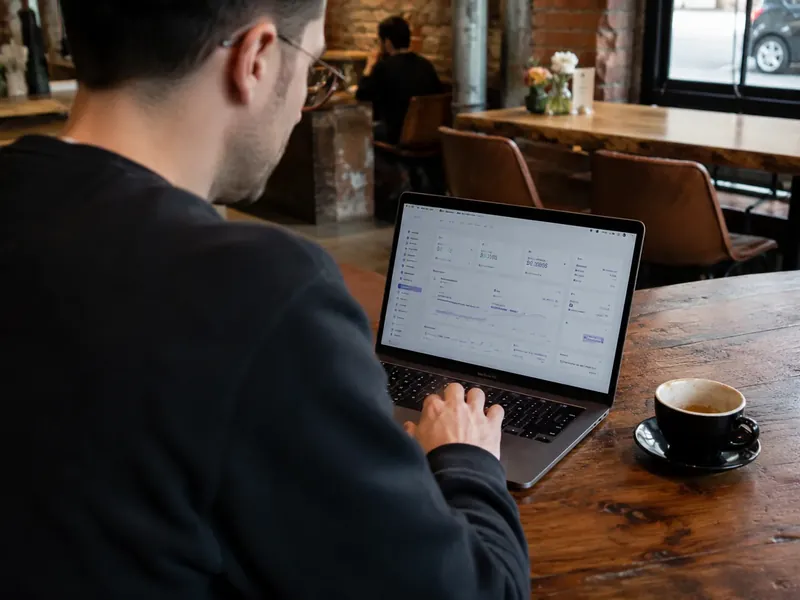 Mann beschreibt am Laptop im Café eine offene Vertriebsstelle